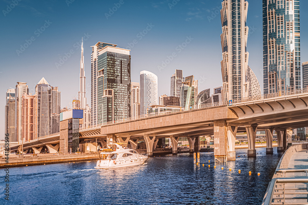 Luxury speedboat sails under the bridge in Dubai Downtown Center with stunning views of numerous skyscrapers and hotels