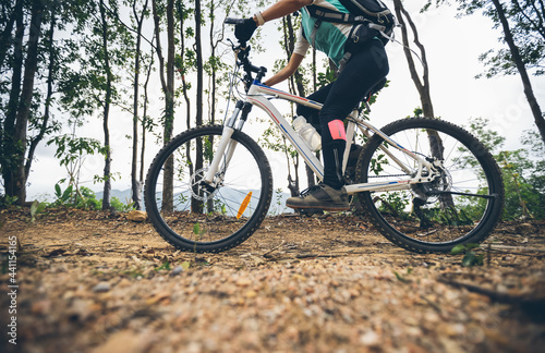 Woman cycling on mountain top forest trail