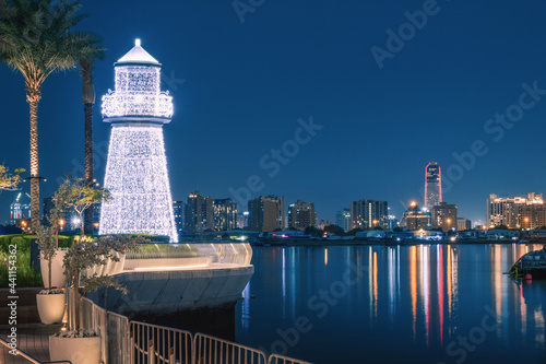 Photography Illuminated decorative lighthouse near the parking lot of yachts and ships in the Dubai Creek Marina Harbor