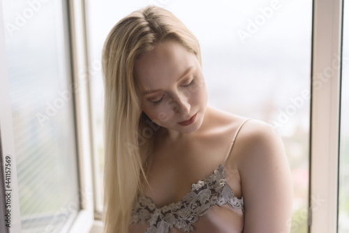 Sad young woman near window.