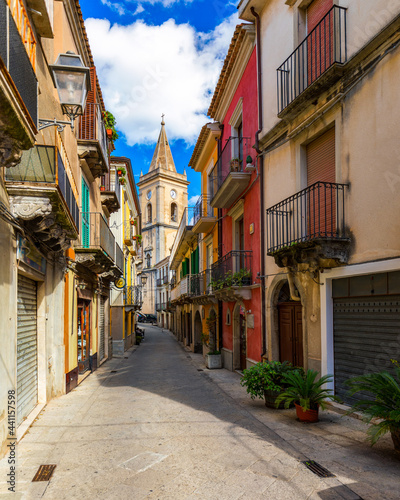 Picturesque street with the Duomo in the background in Novara di Sicilia, Sicily, Italy. Amazing cityscape of Novara di Sicilia town. Mountain village Novara di Sicilia, Sicily, Italy.