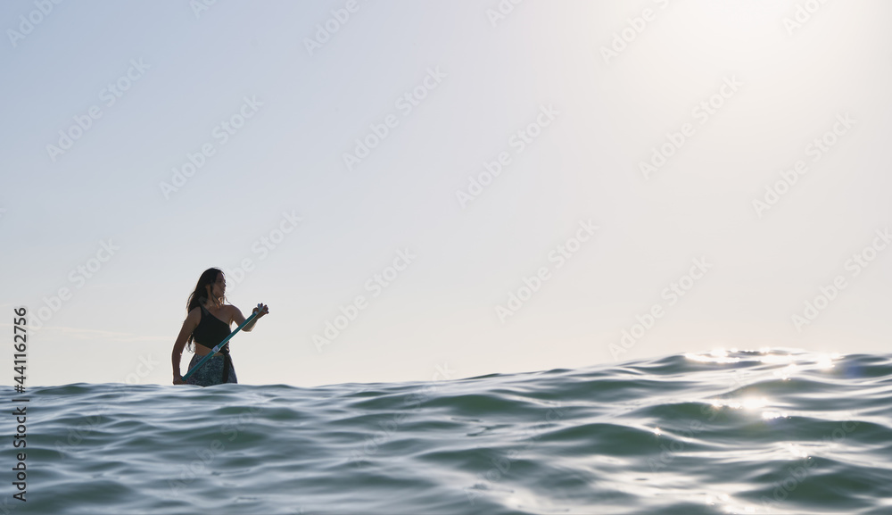 Girl paddling on a paddle board at sunrise
