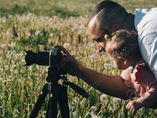 A father shows photographs on a camera to his young child. Dad teaches photography to his daughter.