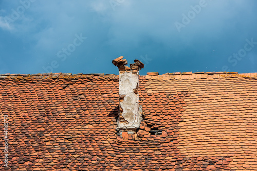 Old brick chimney and roof on a background of the blue sky.