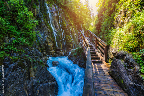 Beautiful Wimbachklamm gorge with wooden path in autumn colors, Ramsau bei Berchtesgaden in Germany. Waterfall at Wimbachklamm near Ramsau-Berchtesgaden, Bavaria, Germany. photo