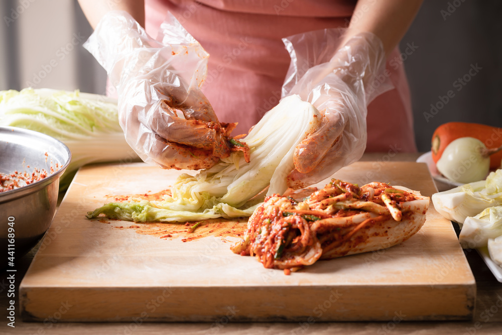 Woman making kimchi cabbage on wooden board, Popular homemade Korean traditional fermented side dish food