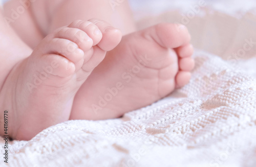 Tiny Babies Feet on White Blanket. Close up of Small Bare Feet of Baby Infant Sleeping on Soft Bed. Cute Newborn Baby Against Knitted Blanket. Childhood. Sleeping Newborn Child