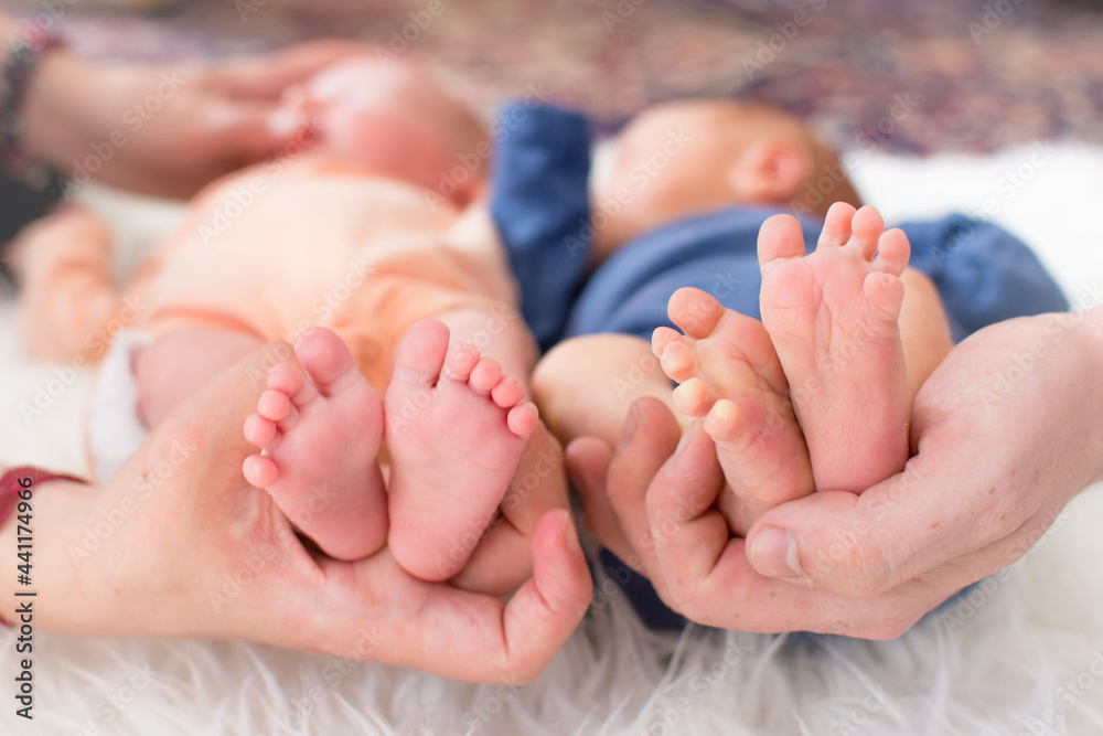 Small feet of newborn premature twins in parent hand and one of baby