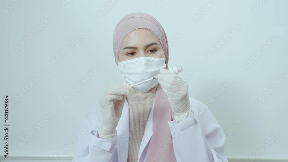 Young female muslim doctor holding a syringe with covid-19 vaccine bottle for injection, covid-19 vaccination and health care concept Young female muslim doctor holding a syringe with covid-19 vaccine bottle for injection, covid-19 vaccination and health care concept