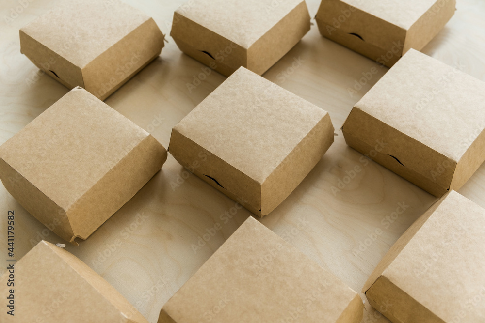 Closeup of kraft paper boxes for burgers on wooden background Closeup of kraft paper boxes for burgers on wooden background
