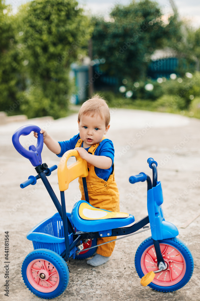 A small boy stands next to a child's tricycle. First bike, new skills A small boy stands next to a child's tricycle. First bike, new skills