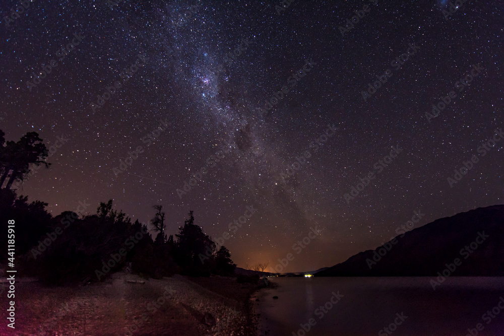 starry sky at night in Los Alerces National Park. Lake Rivadavia can be seen.