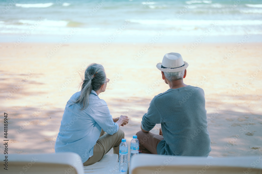Two retired Asian couples relax and chat on the beach.