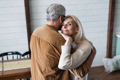 Senior man hugging senior wife at home