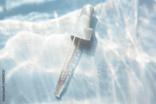 Fotografia Flat lay with a pipette with hydrating serum on a background with underwater effect