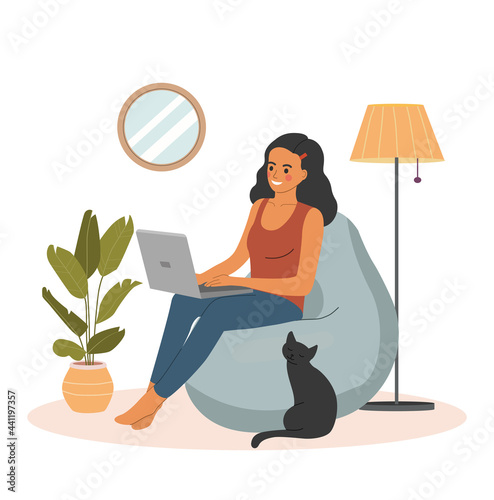 Young woman is relaxing on comfortable beanbag chair and using laptop. Сat is standing next to the chair. Vector flat illustration