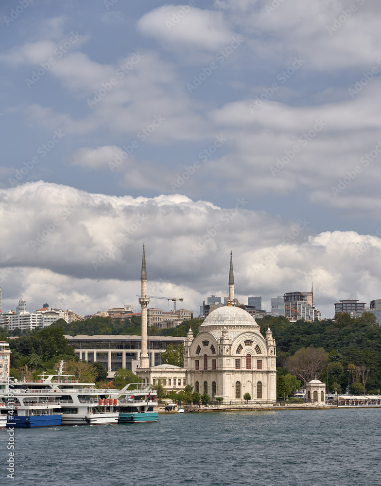 Dolmabahce Mosque view in Istanbul. View from the sea of Dolmabahce Mosque on the banks of the Bosphorus, with Dolmabahce Palace in the distance.