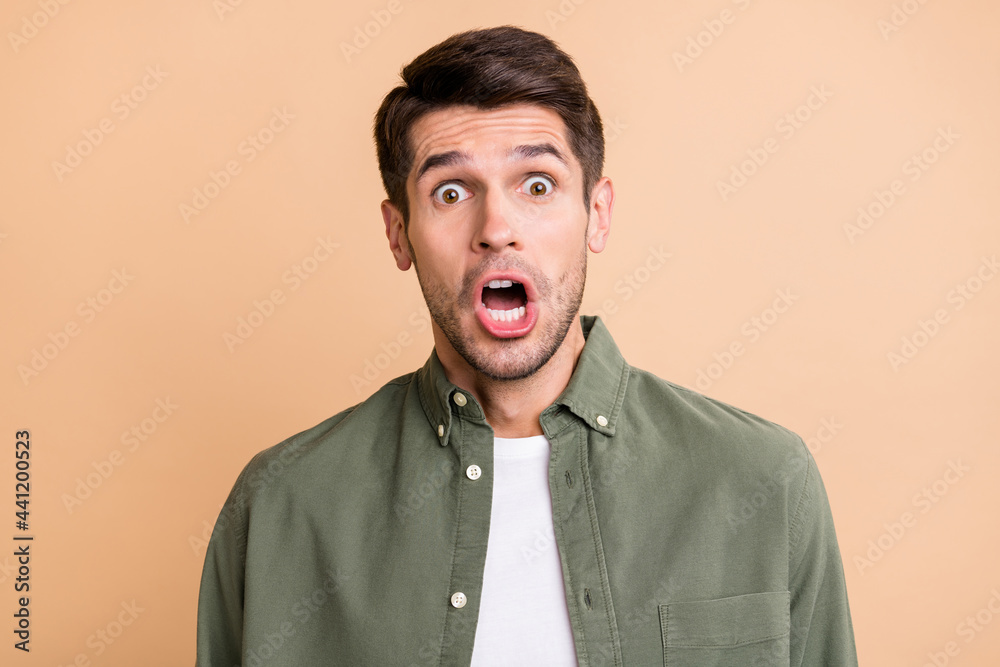 Photo of astonished shocked afraid young man face reaction bad news isolated on beige color background Photo of astonished shocked afraid young man face reaction bad news isolated on beige color background