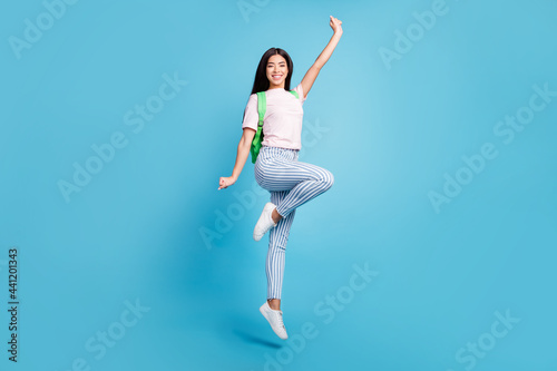 Fototapeta Naklejka Na Ścianę i Meble -  Full length body size view of attractive cheerful teen girl jumping going to high school isolated over bright blue color background