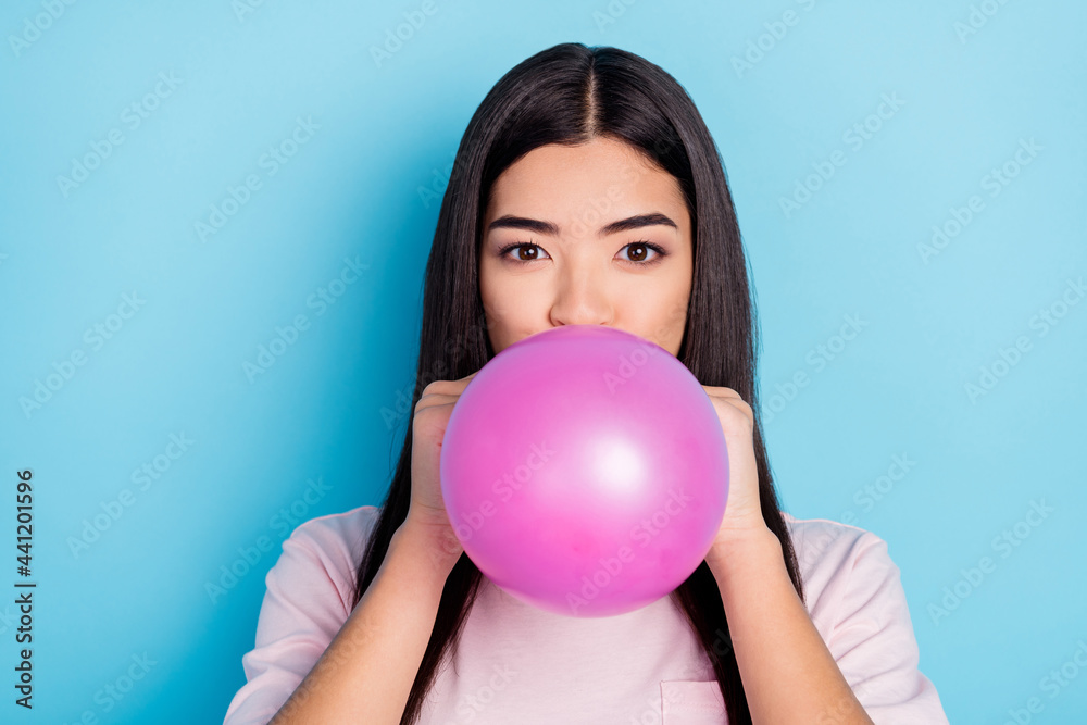 Photo of young girl blow inflate air balloon preparation event celebrate party isolated over blue color background Photo of young girl blow inflate air balloon preparation event celebrate party isolated over blue color background