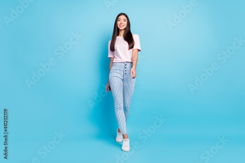 Full length photo of cheerful nice young woman walk weekend good mood smile isolated on blue color background