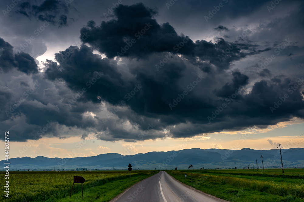 Gathering storm clouds over green agricultural fields, leading asphalt road. Gathering storm clouds over green agricultural fields, leading asphalt road.