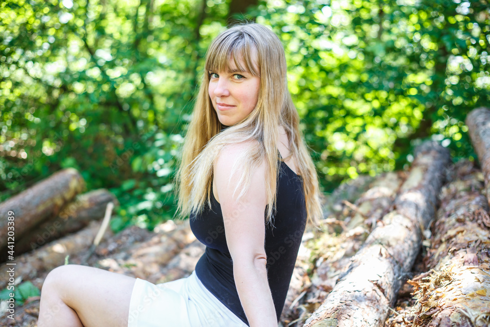 beautiful girl sitting on cut logs in the forest beautiful girl sitting on cut logs in the forest