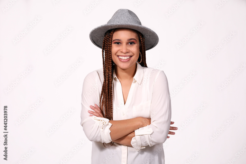 Attractive young woman smiling with arms folded wearing hat on white background Attractive young woman smiling with arms folded wearing hat on white background
