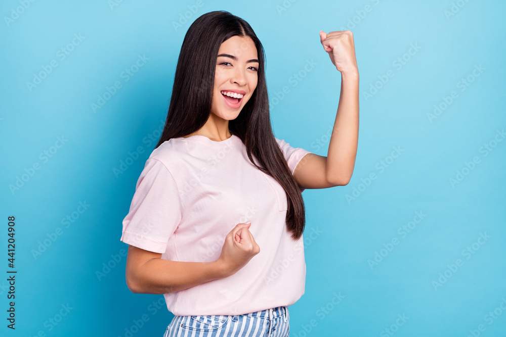 Profile side photo of young girl happy positive smile rejoice victory fists hands success isolated over blue color background Profile side photo of young girl happy positive smile rejoice victory fists hands success isolated over blue color background