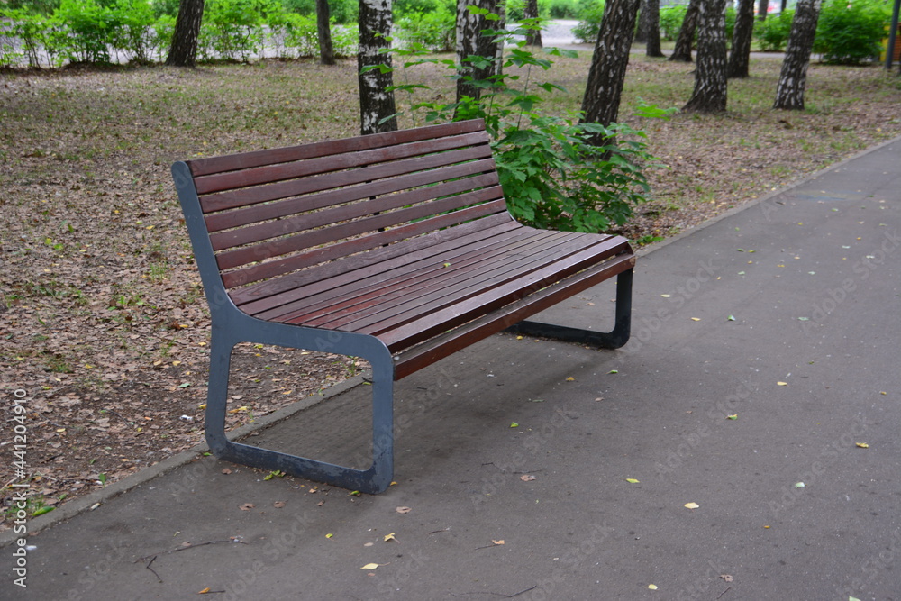 wooden bench in the city park along the path wooden bench in the city park along the path