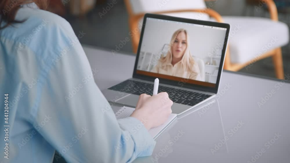 Lady in blue medical coat writes in pad talking with patient Lady in blue medical coat writes in pad talking with patient