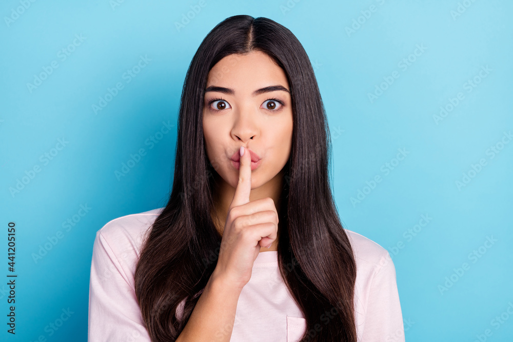 Photo of young attractive asian girl finger cover lips shh keep secret confidential isolated over blue color background Photo of young attractive asian girl finger cover lips shh keep secret confidential isolated over blue color background