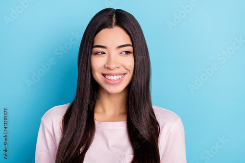 Photo of young cheerful girl happy positive smile interested look empty space isolated over blue color background