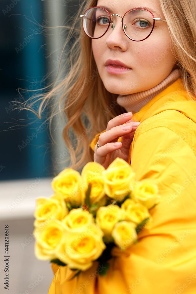 Naklejka premium woman in yellow raincoat with yellow flowers close up in autumn