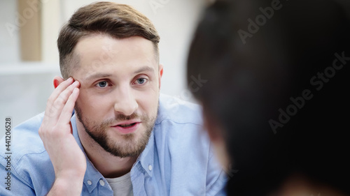 man talking while looking at blurred girlfriend.