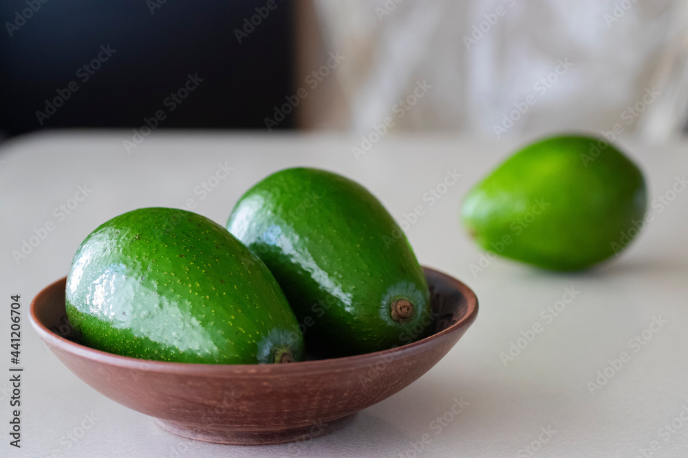 Ripe avocado in a brown plate on a light background. Ripe avocado in a brown plate on a light background.