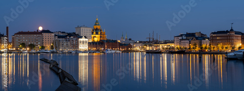 A beautiful night cityscape of downtown Helsinki. Illuminated buildings casting reflections on the calm water.
