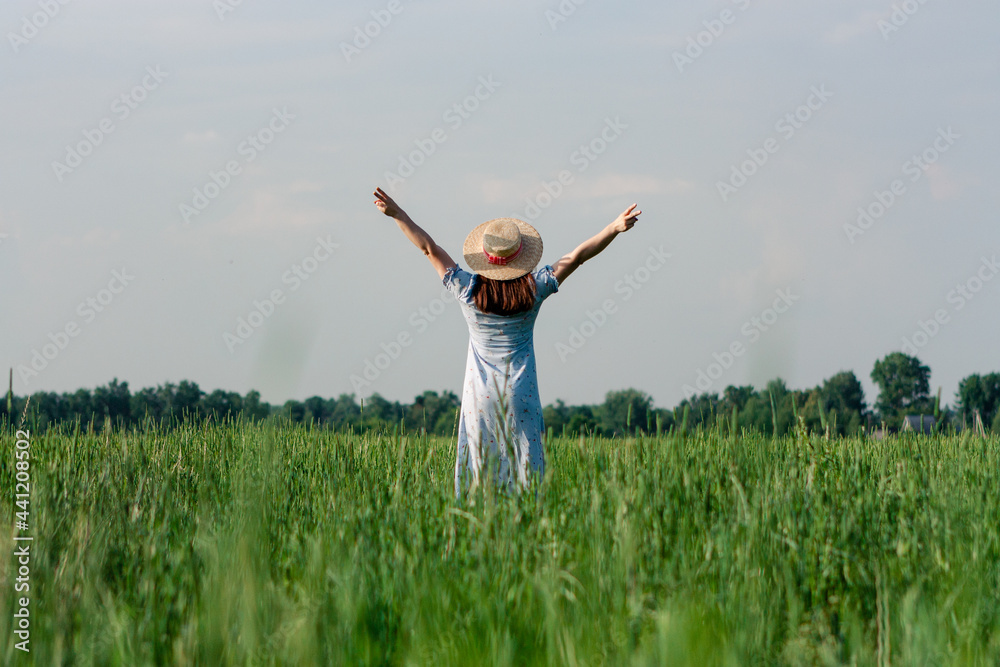 Woman in hat from behind standing in the field Woman in hat from behind standing in the field