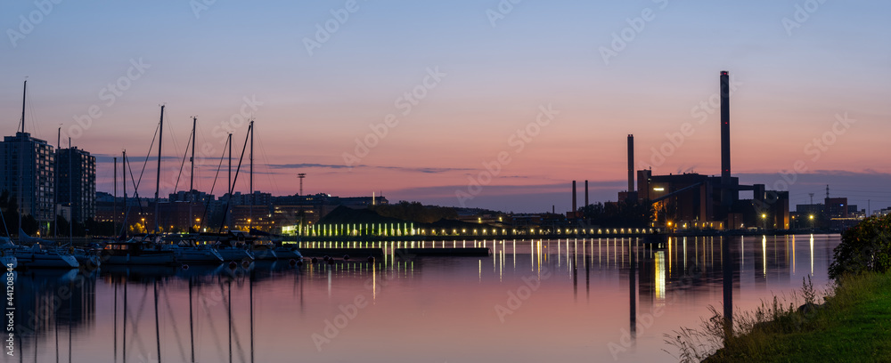 A beautiful night city skyline against colorful sky. An old power plant  casting reflections on the water.
