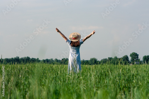 Woman in hat from behind standing in the field