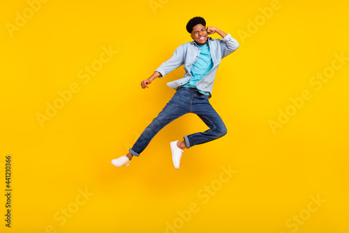 Photo of charming funky dark skin man wear jeans shirt jumping high practicing karate isolated yellow color background