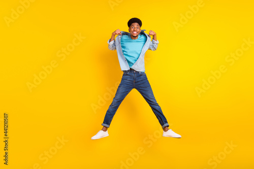 Photo of strong attractive dark skin guy dressed denim shirt showing muscles jumping high isolated yellow color background