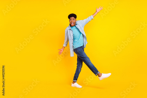 Photo of pretty sweet dark skin man wear jeans shirt dancing walking isolated yellow color background