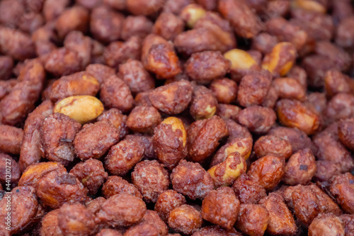 Fototapeta Naklejka Na Ścianę i Meble -  Heap of roasted caramelized sugared peanuts background at summer outdoor food market - close up. Cookery, dessert, gastronomy and street food concept