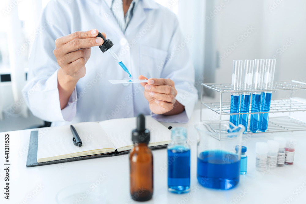 Scientist woman holding dropper to dropping solution sample on the glass plate for microscope Scientist woman holding dropper to dropping solution sample on the glass plate for microscope