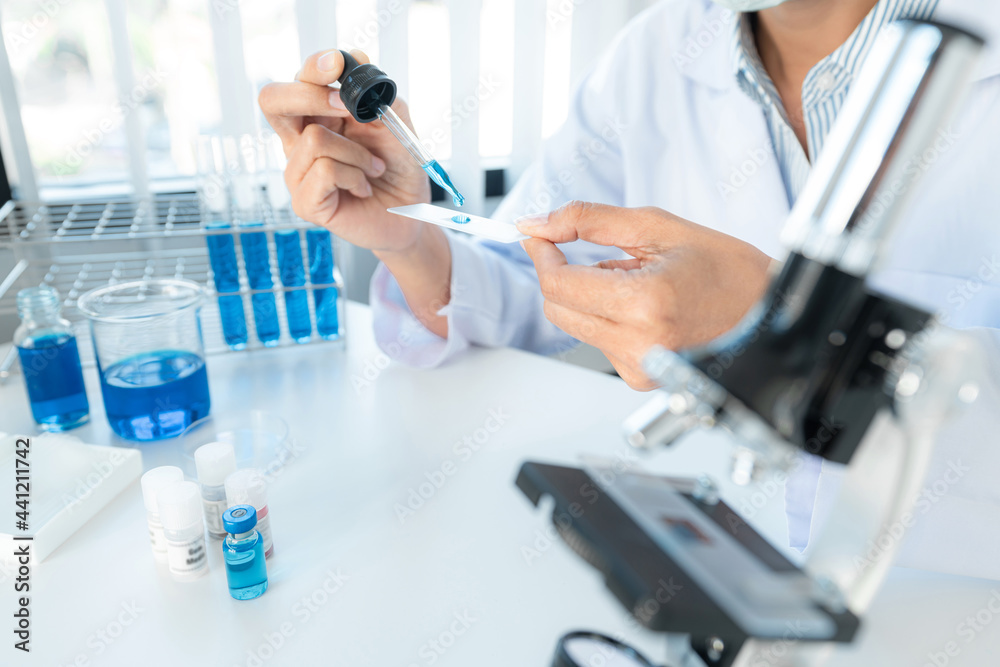 Scientist woman holding dropper to dropping solution sample on the glass plate for microscope to research Scientist woman holding dropper to dropping solution sample on the glass plate for microscope to research