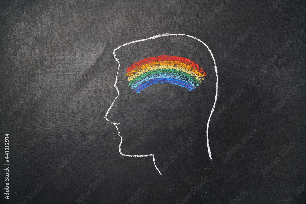 Silhouette of a man's head with a rainbow drawn on a chalk board. Sexual orientation concept.