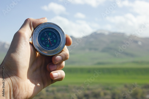 holding a compass on the background of the mountain