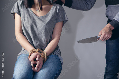 Foto threatens a tied woman with a knife