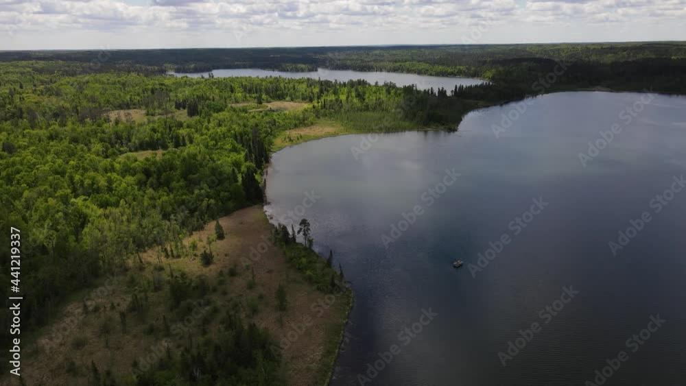 4K flyover of blue, rippling lake with green treed shoreline and forests surrounding it. Pontoon boat can be seen on lake. Lake Itasca, MN. Wide view. 4K flyover of blue, rippling lake with green treed shoreline and forests surrounding it. Pontoon boat can be seen on lake. Lake Itasca, MN. Wide view.